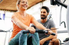 Male personal trainer working with female client in gym
